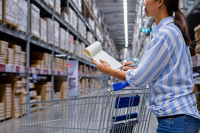 Midsection of woman writing while standing in warehouse