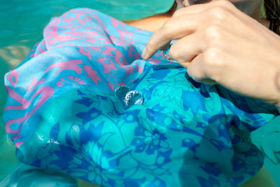 Cropped hand of woman holding crystal on fabric in swimming pool