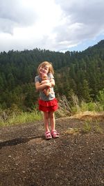 Happy girl standing by tree against sky