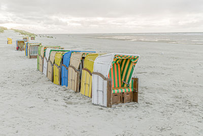 A row of beach chairs on a dull day on empty sandy beach with gray sea and gray sky in background