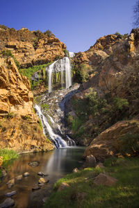 Water flowing through rocks against sky