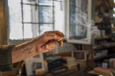 Cropped hand of an old man holding a cigarette