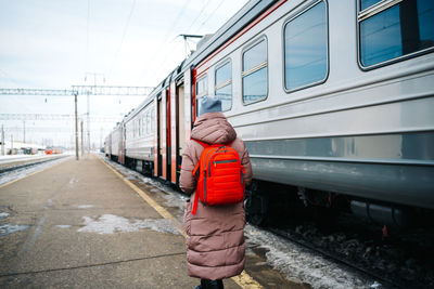 Girl from the back with a backpack on the platform of the station