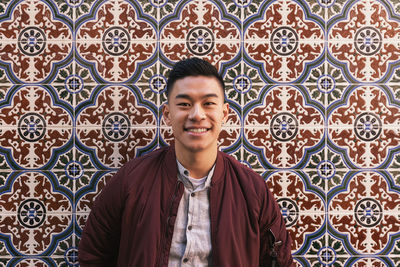 Portrait of young man standing against wall