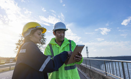 Engineers using digital tablet against sky