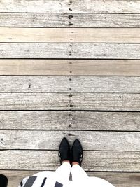 Low section of person standing on boardwalk