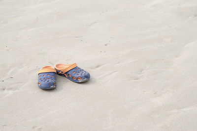 Close-up of sandals on sand at beach