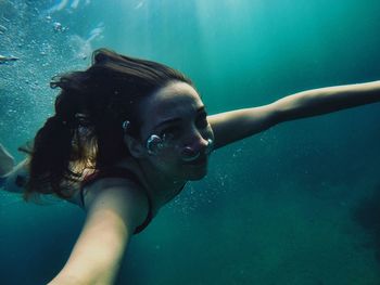 Smiling woman swimming underwater in sea
