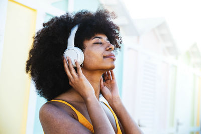 Relaxed afro woman listening music through headphones