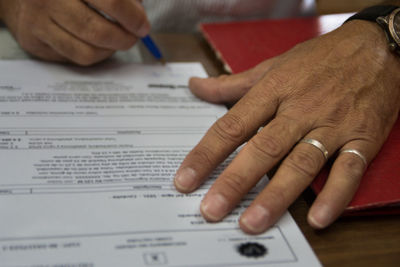 Cropped image of man signing paperwork on table