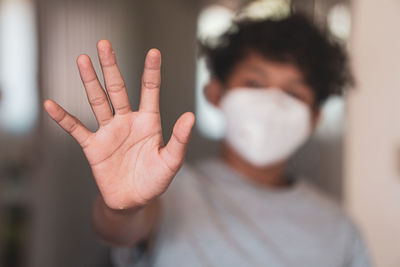 Close-up of boy showing stop gesture while wearing mask