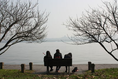 People sitting on bench by lake