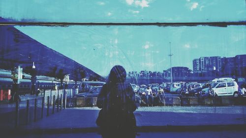 Woman standing by city against sky