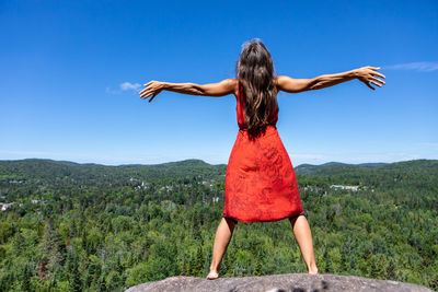 Rear view of woman with arms outstretched against mountain