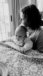 Rear view of mother and daughter on bed at home