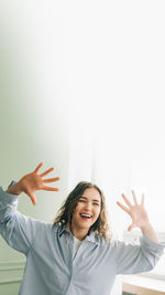 Portrait of young woman with arms crossed against white background