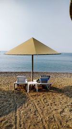 Chair on beach against clear sky