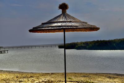Scenic view of beach on lake with parasol against sky