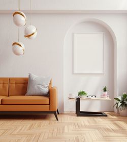 Poster mock up with vertical empty white frames and leather orange sofa.3d rendering