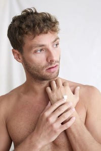 Portrait of shirtless young man against white background