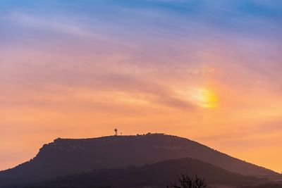 Scenic view of silhouette mountains against orange sky