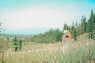 Rear view of woman standing on field against sky