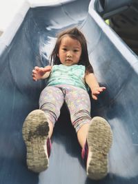 Low angle portrait of girl on slide at playground
