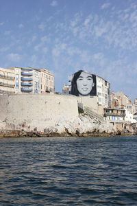 Graffiti on building by sea against sky in city