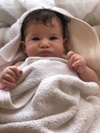 Portrait of cute baby lying on bed at home