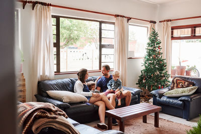 Parents and kids sitting on sofa at home