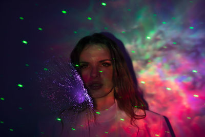 Portrait of beautiful woman standing against illuminated light