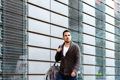 Young bearded man walking on the street next to office building