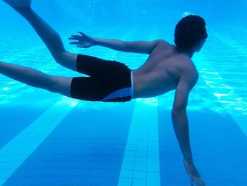 Shirtless teenage boy swimming in pool