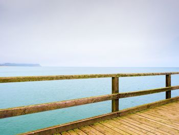 Empty mole. autumn morning on wooden pier above sea. depression, dark atmosphere. touristic mole