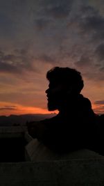 Silhouette man looking at camera against sky during sunset