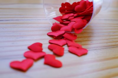 Close-up of red heart shape spilling from glass on table
