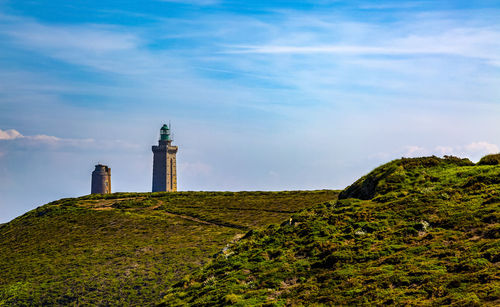 Lighthouse by building against sky