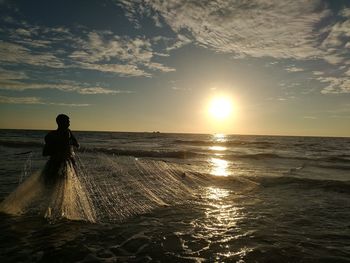 Silhouette man on beach against sky during sunset