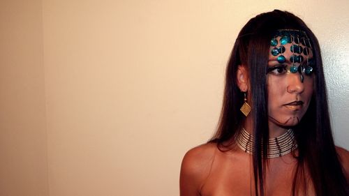 Close-up of woman in tribal costume during halloween by wall