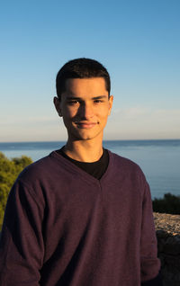 Portrait of young man standing against sea