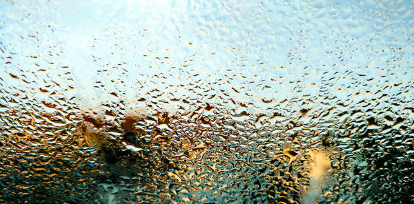 Full frame shot of wet window against sky