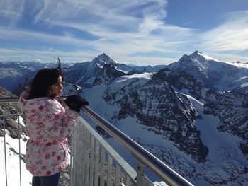 Teenage girl standing at observation point against snowcapped mountains