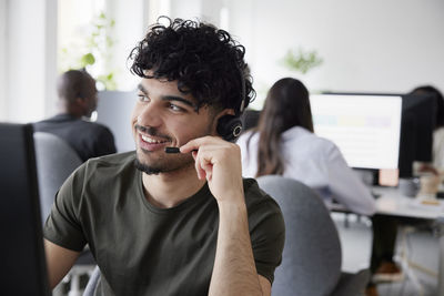 Man wearing headset using desktop pc in office