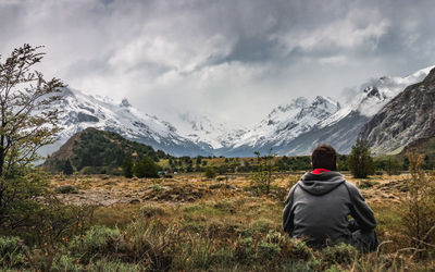 Rear view of person on snowcapped mountain against sky