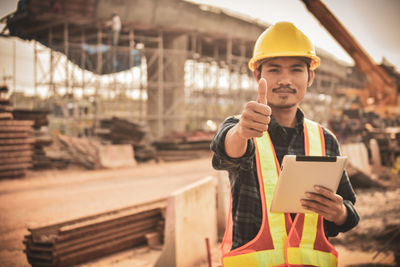 Portrait of architect holding digital tablet showing thumbs up at site