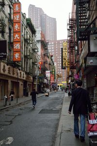 People walking on city street against buildings