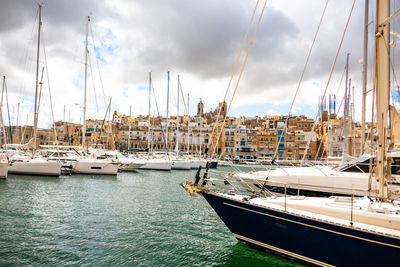 Sailboats moored at harbor against sky