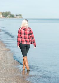 Rear view of woman with umbrella walking on beach