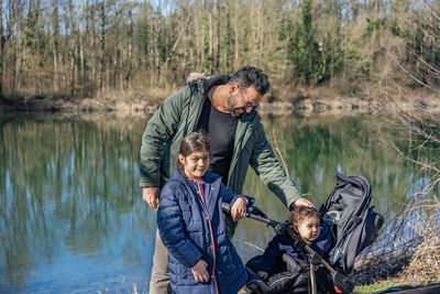 Close-up of father with stroller and two children walking along the aare river in springtime.