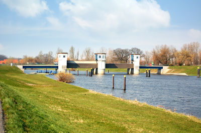 Bridge over river amidst field against sky